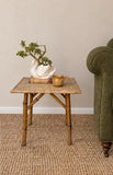 Vintage tiger bamboo side table styled beside an olive green armchair 